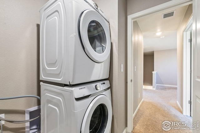 clothes washing area with laundry area, visible vents, baseboards, stacked washing maching and dryer, and carpet