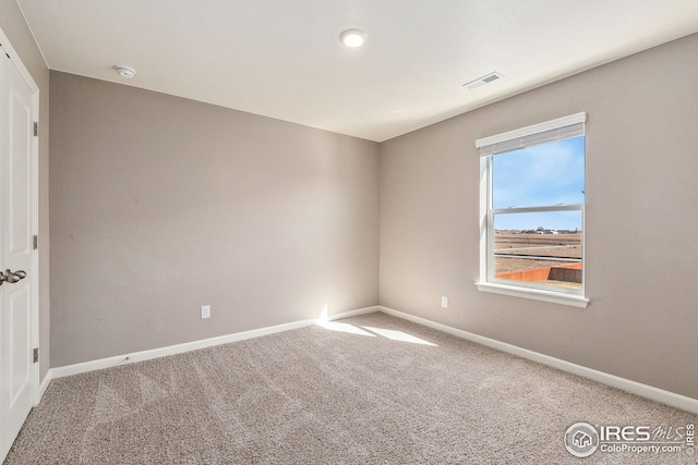 carpeted spare room featuring visible vents and baseboards