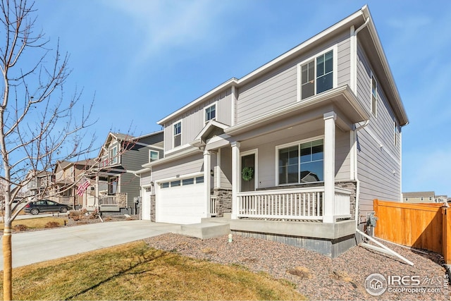 view of front of property featuring driveway, stone siding, an attached garage, fence, and a porch