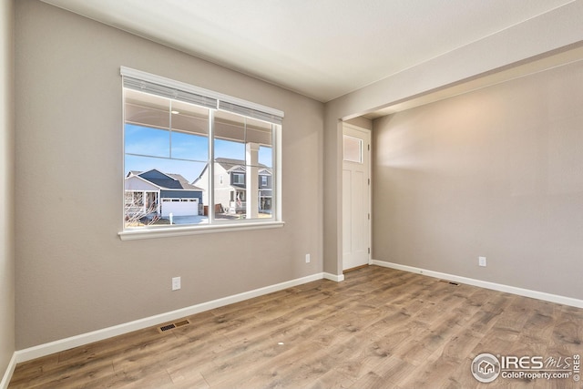 spare room featuring visible vents, baseboards, and wood finished floors