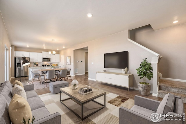 living area featuring light wood finished floors, visible vents, stairway, and a notable chandelier