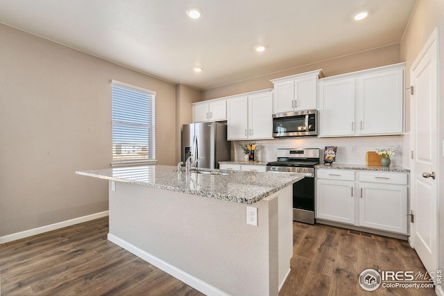 kitchen featuring a kitchen island with sink, dark wood-style flooring, stainless steel appliances, and decorative backsplash