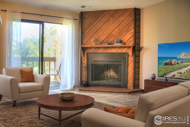 living area featuring a large fireplace, visible vents, and a textured ceiling