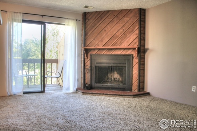 unfurnished living room with a textured ceiling, carpet, a fireplace, and a wealth of natural light