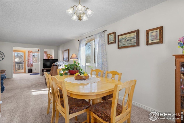 dining area featuring a chandelier, a textured ceiling, baseboards, and light colored carpet