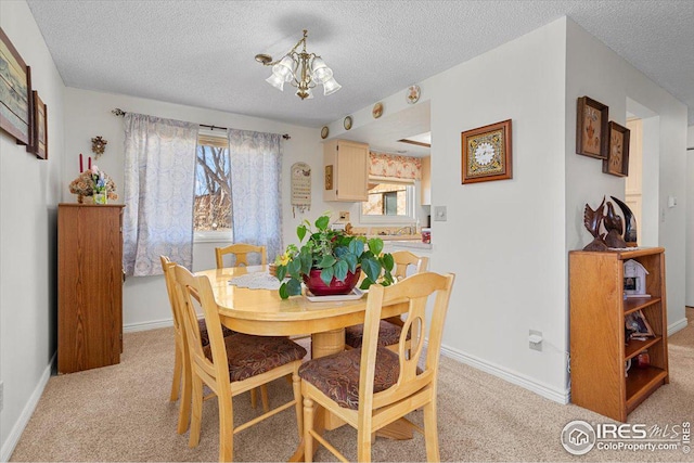 dining room featuring light carpet, baseboards, a chandelier, and a textured ceiling