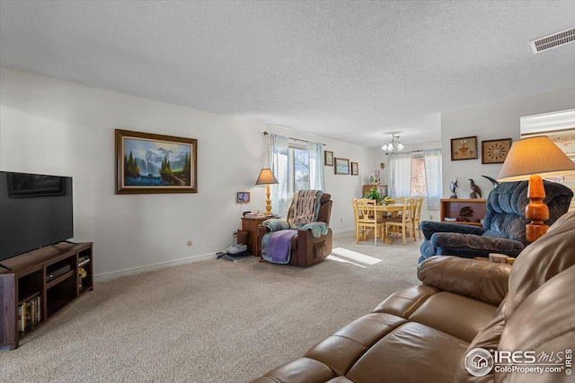 living area with carpet floors, visible vents, an inviting chandelier, a textured ceiling, and baseboards