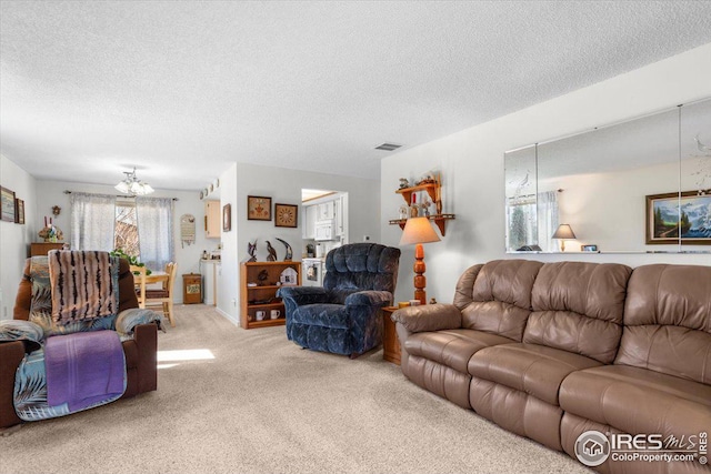 living area with a textured ceiling, a notable chandelier, visible vents, and light colored carpet