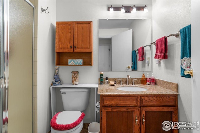 bathroom featuring toilet, a stall shower, and vanity