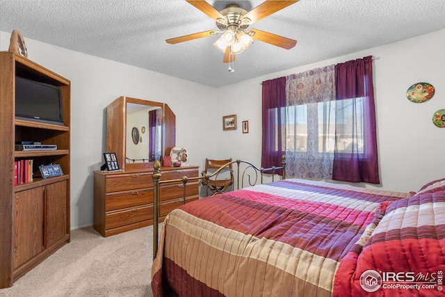 carpeted bedroom featuring ceiling fan and a textured ceiling