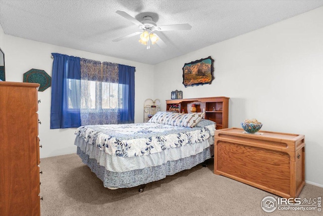 carpeted bedroom featuring ceiling fan and a textured ceiling