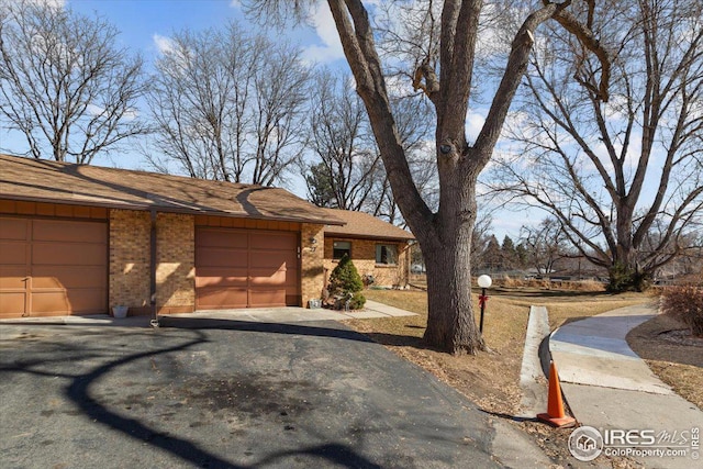 view of front of house featuring a garage, aphalt driveway, and brick siding