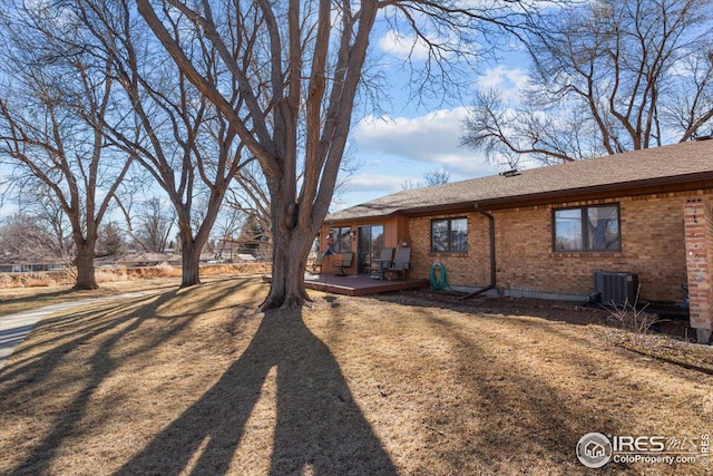 view of home's exterior with a yard, a deck, central AC, and brick siding