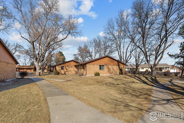 view of front of property featuring fence, a front lawn, and brick siding