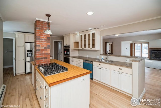 kitchen with butcher block countertops, stainless steel appliances, crown molding, light wood-type flooring, and a sink