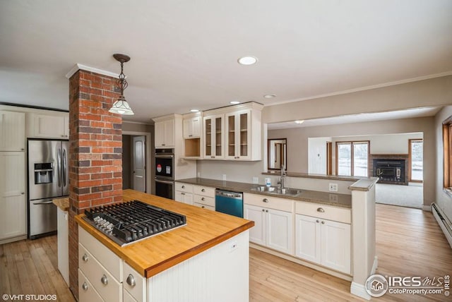 kitchen with stainless steel appliances, light wood-style floors, open floor plan, a sink, and a peninsula