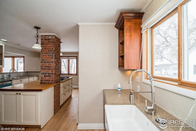 kitchen featuring light wood-type flooring, decorative columns, wood counters, and a sink