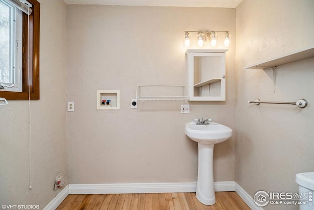 bathroom with a wealth of natural light, wood finished floors, toilet, and baseboards