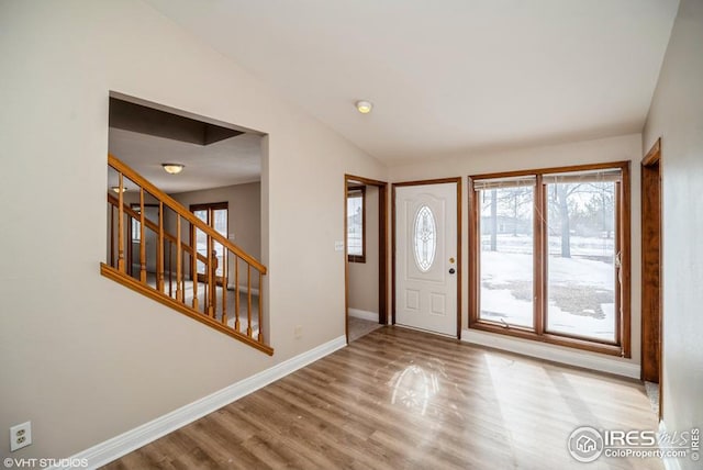 foyer with lofted ceiling, stairway, baseboards, and wood finished floors