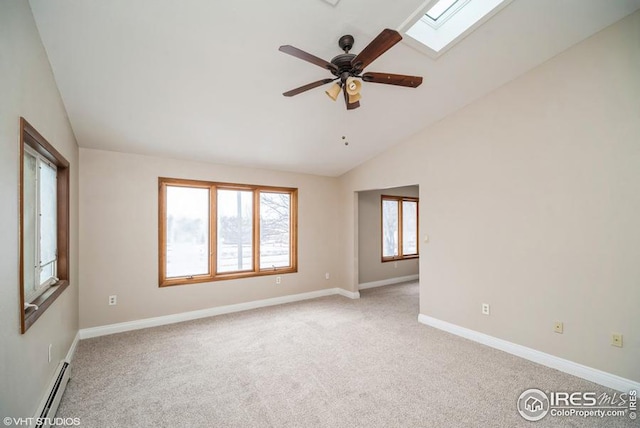 spare room featuring a baseboard heating unit, vaulted ceiling with skylight, light colored carpet, and baseboards