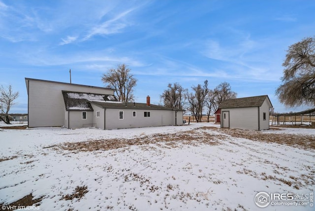 snow covered house with a detached garage and an outdoor structure