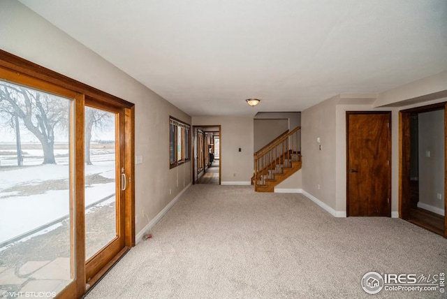 unfurnished room with light carpet, baseboards, and stairway