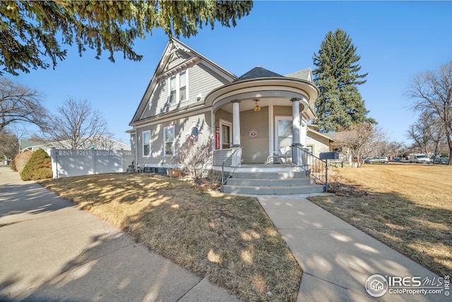 victorian-style house featuring covered porch and a front lawn