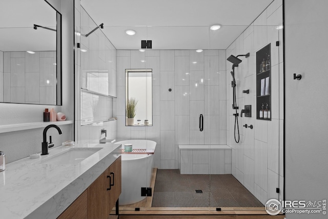 bathroom with a stall shower, a freestanding tub, and vanity