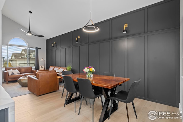 dining room featuring ceiling fan, light wood-style floors, and a decorative wall