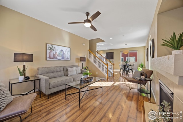 living area with ceiling fan, wood finished floors, stairs, a fireplace, and recessed lighting