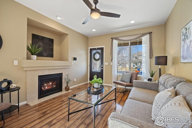 living room featuring a fireplace, baseboards, wood finished floors, and recessed lighting