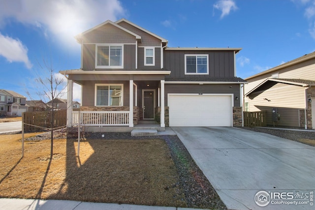 craftsman inspired home with a garage, concrete driveway, stone siding, a porch, and board and batten siding