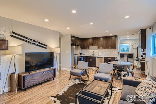 living area with baseboards, recessed lighting, and light wood-style floors