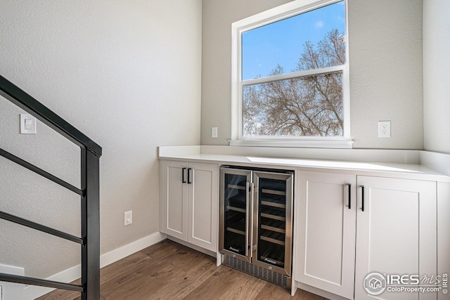 bar featuring wine cooler, baseboards, and wood finished floors