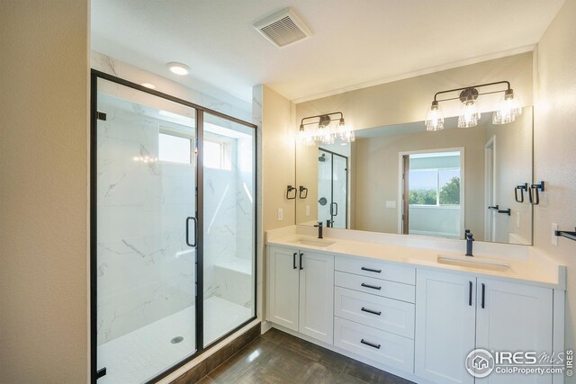 full bath with visible vents, a sink, a marble finish shower, and double vanity