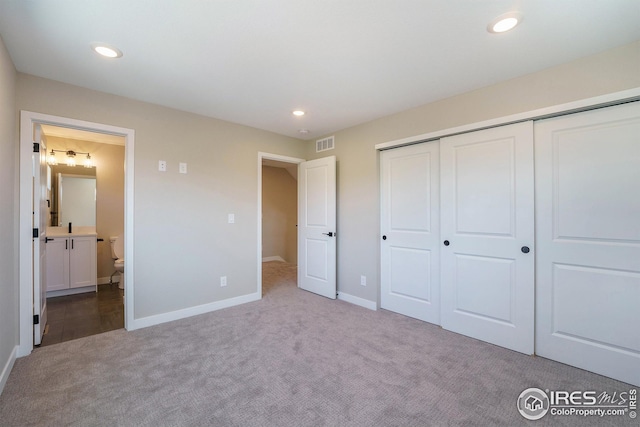 unfurnished bedroom with ensuite bathroom, recessed lighting, visible vents, a closet, and carpet