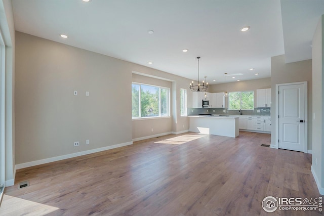 kitchen with a healthy amount of sunlight, visible vents, stainless steel microwave, and white cabinets