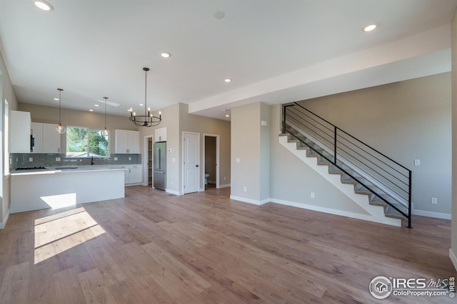 kitchen with white cabinets, high quality fridge, light countertops, light wood-style floors, and backsplash
