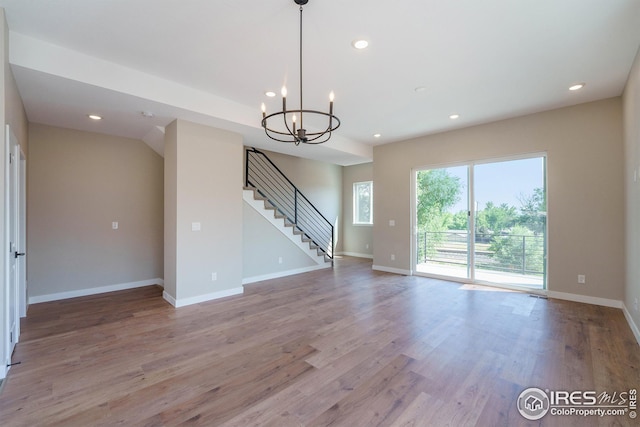 unfurnished living room with baseboards, stairway, light wood-style floors, a notable chandelier, and recessed lighting