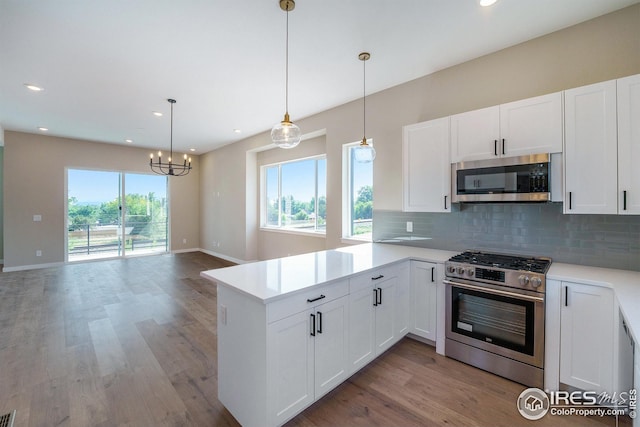 kitchen with tasteful backsplash, appliances with stainless steel finishes, a peninsula, light countertops, and light wood-style floors