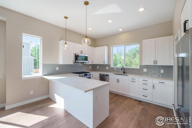 kitchen with stainless steel appliances, backsplash, light wood-style floors, and a peninsula