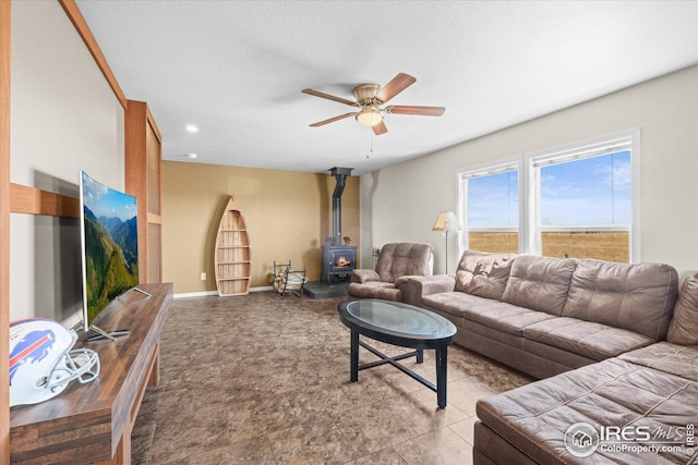 living room with recessed lighting, a wood stove, ceiling fan, a textured ceiling, and baseboards