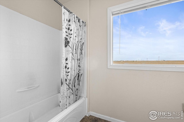 bathroom featuring baseboards and shower / tub combo with curtain