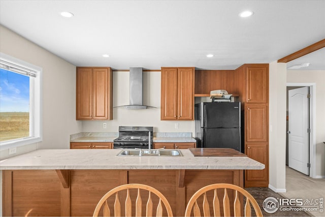 kitchen featuring black appliances, wall chimney range hood, light countertops, and a sink