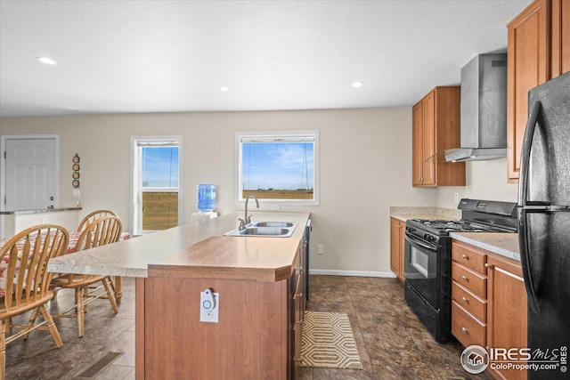 kitchen featuring brown cabinetry, wall chimney exhaust hood, a sink, and black appliances