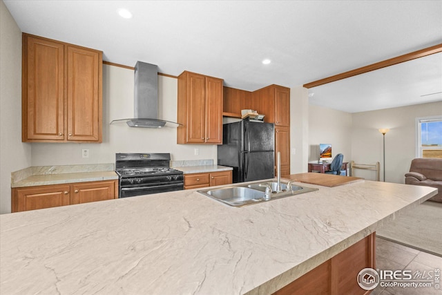 kitchen with a sink, light countertops, wall chimney range hood, black appliances, and brown cabinetry