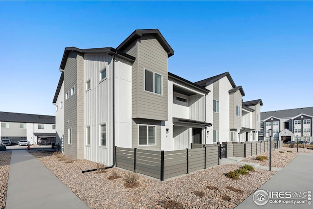 view of front of property with a residential view, fence, and board and batten siding