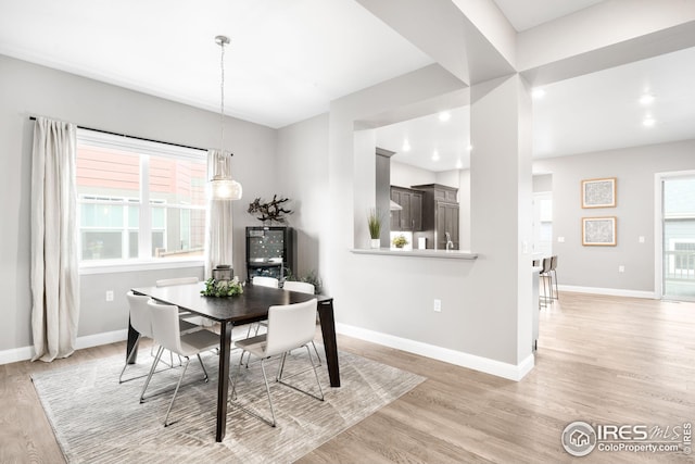 dining space with baseboards, a healthy amount of sunlight, and light wood-type flooring