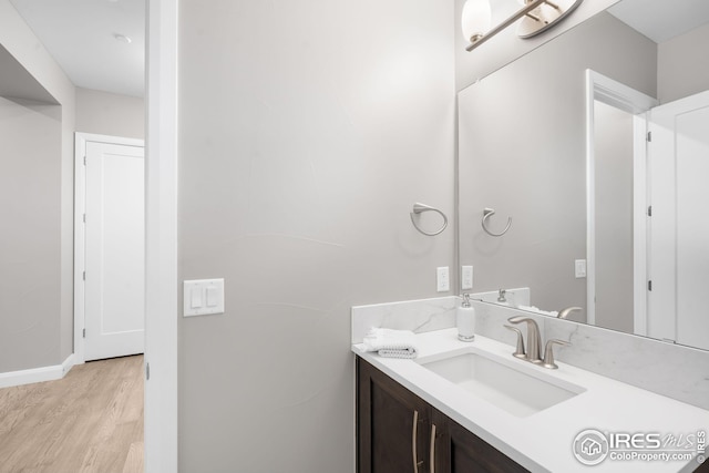 bathroom featuring baseboards, wood finished floors, and vanity