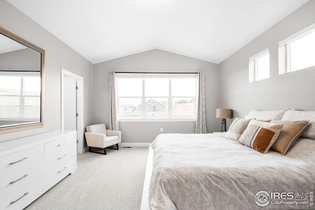 bedroom featuring baseboards, lofted ceiling, and light carpet